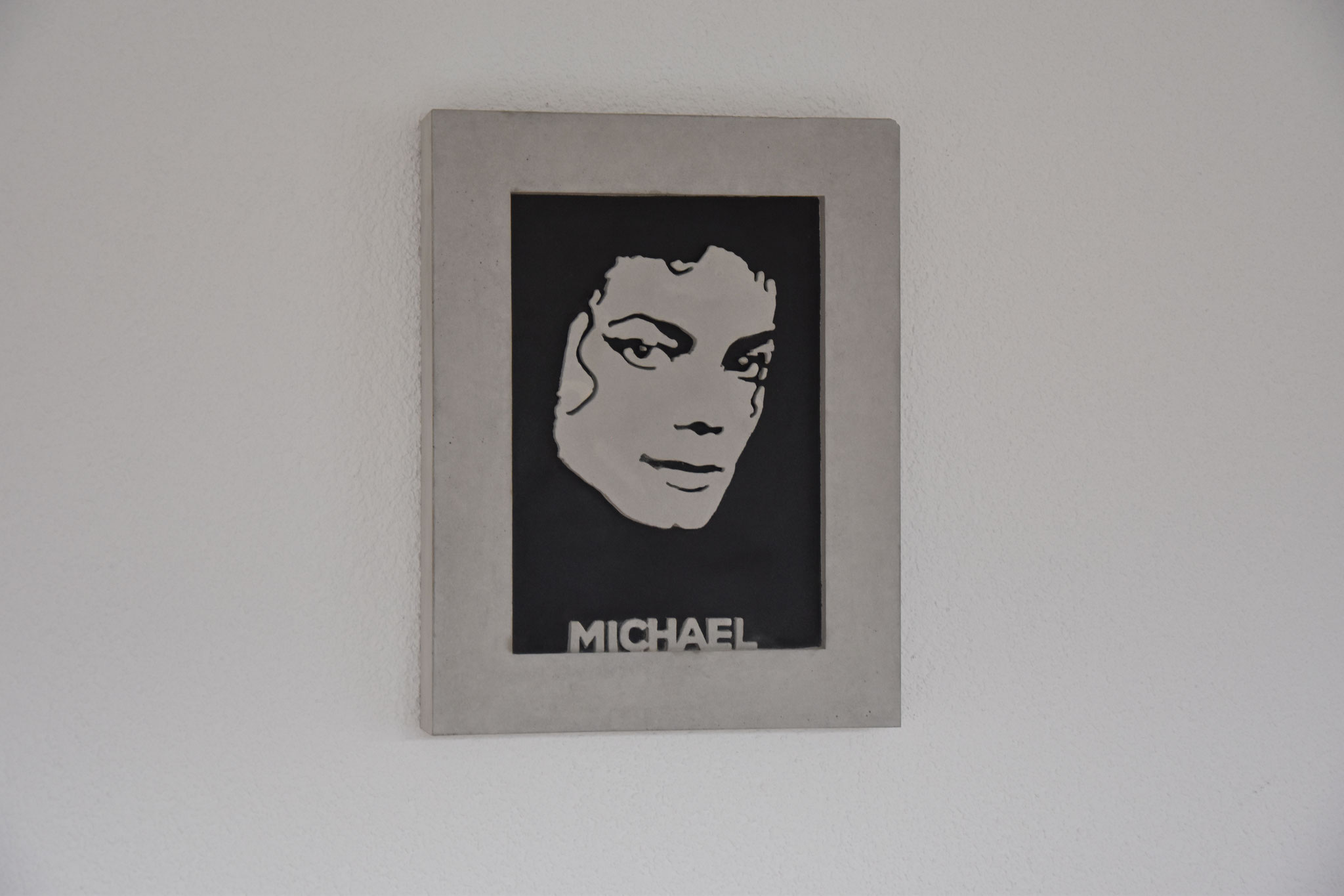 Betonportrait von Michael Jackson mit detaillierter Silhouette auf schwarzem Hintergrund, eingerahmt in Beton.